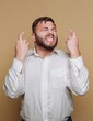 © bodnarphoto - Man expressing intense emotions with crossed fingers and a hopeful smile in a cozy studio background