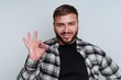 © bodnarphoto - Young man in plaid shirt happily making an okay gesture with a friendly smile against a simple background
