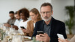 © pattozher - Digital Distraction: A group of individuals is immersed in the glow of their smartphones, gathered at a table, lost in a world of digital communication and connectivity.