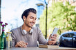 © Westend61 - Happy young man using cell phone at outdoors cafe