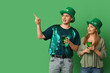 © Pixel-Shot - Happy friends with beer pointing at something on green background. St. Patrick's Day celebration