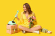 © Pixel-Shot - Young woman with retro telephone, bouquet of beautiful tulips and gift boxes on yellow background. International Women's Day