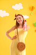 © Pixel-Shot - Young woman with soda near decorated yellow wall. Valentine's Day celebration