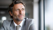 © Denis Yevtekhov - Happy confident mature 45-year-old businessman investor standing in office looking away, middle-aged rich business owner male CEO executive leader, wearing suit thinking on future