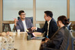 © Johnér - Young male colleague discussing with manager while sitting around table in meeting room