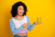 © deagreez - Smiling young woman holding a golden crown against a yellow background, expressing joy, elegance, and modern style