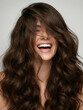 © yuliachupina - Woman laughing with long wavy hair in a light background