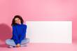 © deagreez - Young chic woman in blue pullover sits on pink background with white board smiling for lifestyle fashion stock photo