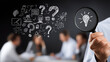 © Techno Stoks - man using a magnifying glass to highlight a glowing light bulb with question marks on a black background