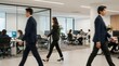 © Abdul - Professionals walking through a modern office space with colleagues working at desks