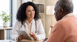 © Eduardo Accorinti - Female doctor explaining medical information to senior patient using tablet during consultation in medical office with natural window light