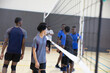 © wavebreak3 - Diverse teenage male rival volleyball teams shaking hands across net in school gym wearing jerseys