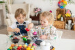 © Tomsickova - Happy childen, siblings, coloring eggs for Easter at home, sunny room