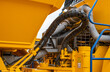 © NastyaPhoto - Close-up of a hydraulic hose system and cooling radiator on a yellow mining dump truck. Heavy industrial machinery components, hydraulic lines with protective sleeves on a massive vehicle.