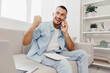 © SHOTPRIME STUDIO - Excited man celebrating success while on the phone, casual style, bright setting, contemporary decor, showcasing happiness and achievement.