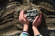 © Мар'ян Філь - Young boy, explorer, explores stones on the ocean shore, digs up old stones in the sand with his hands. Children's hands and old stone, sand on seashore