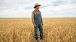 © spyrakot - Young adult in work clothes and straw hat standing in golden wheat field