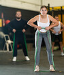 © JackF - Motivated sporty young woman doing exercises with elastic loop band during intense cross workout with group in gym..