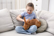 © New Africa - Girl with cute bunny on sofa at home