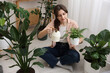 © New Africa - Woman watering beautiful potted houseplant at home