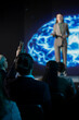 © DC Studio - Selective focus of male participant asking AI-related question, interacting with businesswoman presenter during sales pitch for artificial intelligence systems. Audience engagement at event.