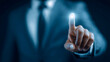 © estrel - of a businessman in a blue suit with a raised index finger in contact with a floating interface above his finger Dark blue monochrome background