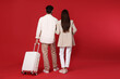 © New Africa - Happy couple with suitcase on red background, back view. Space for text