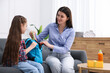 © New Africa - Mother and daughter packing backpack for school on sofa at home