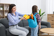 © New Africa - Mother helping her daughter to pack backpack for school on sofa at home