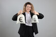 © New Africa - Happy businesswoman holding bags with money on grey background. Dollar and euro currency symbols on fabric