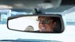 © Vlad - Happy young man in stylish glasses driving car and looking at rear view mirror. Transport and lifestyle concept. Slow motion