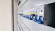 © VladyslavShcherbakov - Row of blue circuit breakers inside electrical distribution panel. Close-up of power control system in industrial or commercial building.