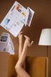 © Pixel-Shot - Legs of woman in high heels with lamp and many newspapers on armchair against brown background