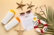 © Pixel-Shot - Calendar with sunglasses, palm leaf and beach decor on light yellow background. Summer vacation concept
