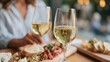 © liliyabatyrova - Friends gather around a beautiful wooden table, enjoying a charcuterie board filled with cheeses, meats, and fresh bread. Laughter fills the air as they sip white wine and savor delicious bites