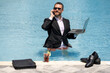 © Volodymyr - Crazy Summer business. Businessman in suit wit laptop in swimming pool. Crazy summer freelancer working in pool. Fun and comic leadership moment. Handsome entrepreneur in water. Motivated freelancer.