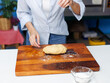 © Bangkok Click Studio - Asian woman bakers sprinkling dough with flour on wooden cutting board preparing during baking process in bakery kitchen ingredients making homemade bread pastry sweet dessert enjoying cooking concept