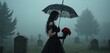 © Pete - Gothic woman in black dress holding umbrella and red roses stands in foggy cemetery. She is alone among graves with tombstones and trees. Dark moody scene.
