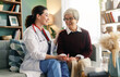 © Konstantin Yuganov - Smiling Female Doctor Provides Compassionate Home Care to Senior Woman in Living Room