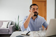 © kleberpicui - Man sitting at desk resting face on hand while looking bored at laptop screen during slow work moment in home workspace with coffee and laptop.