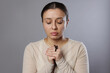 © New Africa - Woman with cross praying on light grey background