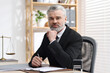 © New Africa - Portrait of handsome notary in suit with pen at table in office
