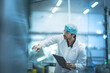 © ultramansk - A quality assurance (QA) specialist audits inventory in a smart factory warehouse. He checks a stack of cans for the automated production line, ensuring compliance.
