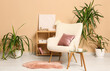 © Pixel-Shot - Armchair with coral cushion near beige wall in interior of living room