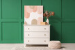 © Pixel-Shot - Chest of drawers with decor and pouf near green wall in room