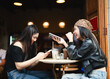 © dodotone - Two young asian woman gen z using smartphone share lifestyle happiness travel moment on social media in Bangkok