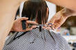 © Azyasseva Olga - Close-up of a barber cutting dark wet hair with professional scissors and a comb. Professional haircut process in a modern barbershop.