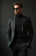 © Pete - Man in black suit and turtleneck wears sunglasses. He poses with hands in pockets against dark studio background. Confident executive looks serious, powerful. Stylish professional man.