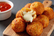 © Alex & M Studio - Crispy golden fried cheese balls with melted mozzarella center served on a wooden cutting board with a bowl of red marinara dipping sauce for a party snack