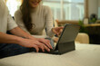 © saltdium - Hands of a couple typing and pointing at a tablet screen, representing teamwork, online communication, and connected living